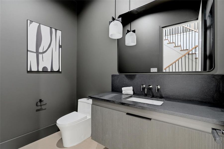 Powder room featuring a sleek floating vanity with a dark countertop and integrated sink