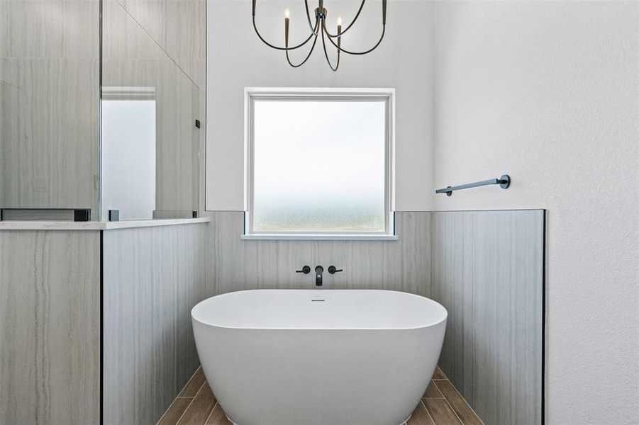 Bathroom featuring a soaking tub, a chandelier, wood tiled floors, and wainscoting Bathroom featuring a soaking tub, a chandelier, wood tiled floors, and wainscoting