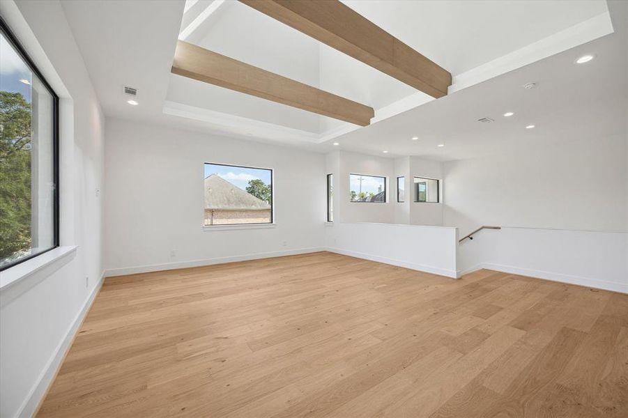 Beautiful beams span the tall vaulted loft ceiling stained to match the flooring.