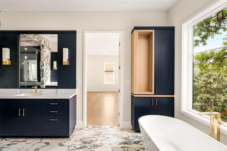 Primary bath with striking contrast, featuring fluted navy cabinetry, quartzite surfaces, and warm white oak accents.