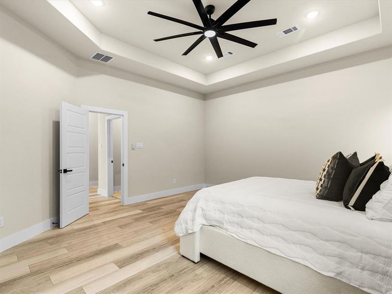 Bedroom featuring a tray ceiling, light wood-style flooring, recessed lighting, and ceiling fan