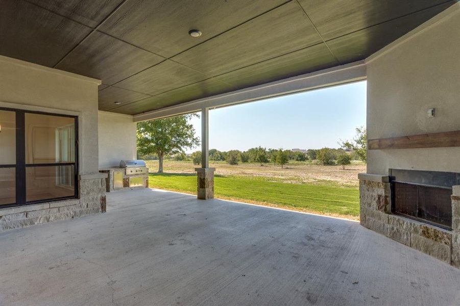 View of patio / terrace with exterior fireplace, area for grilling, and a rural view