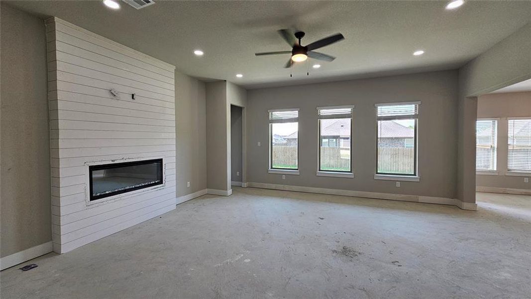 Unfurnished living room with ceiling fan, a textured ceiling, and a large fireplace