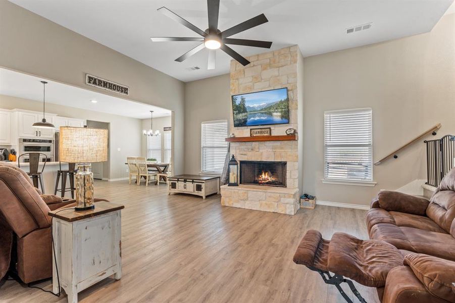 Living area featuring a fireplace, light wood-style flooring, and ceiling fan Living area featuring a fireplace, light wood-style flooring, and ceiling fan