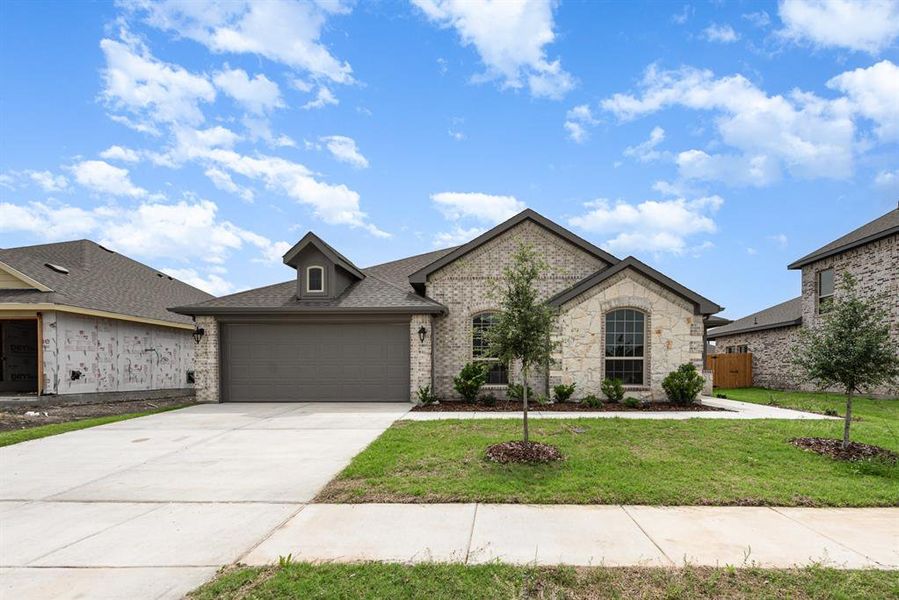 French country style house featuring a garage and a front yard