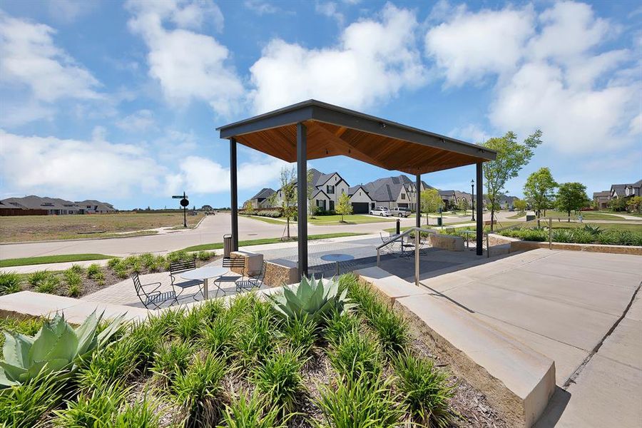 Modern outdoor pavilion with a wood-finish ceiling, dark metal supports, and integrated overhead lighting
