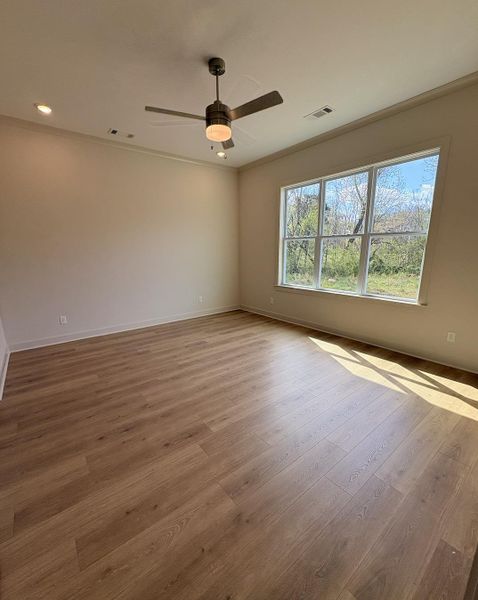 Unfurnished room featuring light wood-style floors, a ceiling fan, and crown molding
