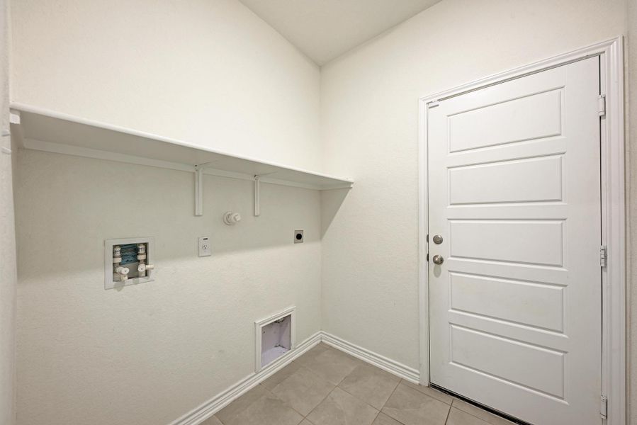 Functional utility room with tiled floors and ample shelving offers practical living.