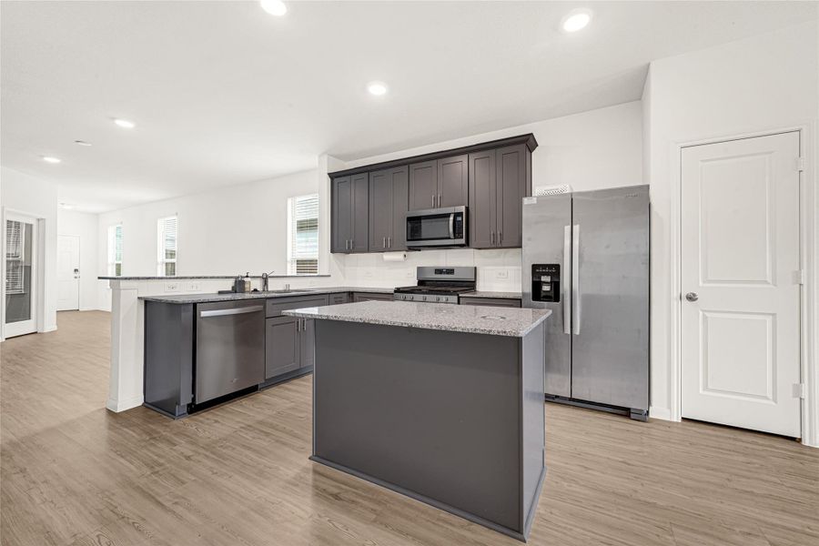 Alternate view of the kitchen showcasing the large central island and ample cabinetry space.
