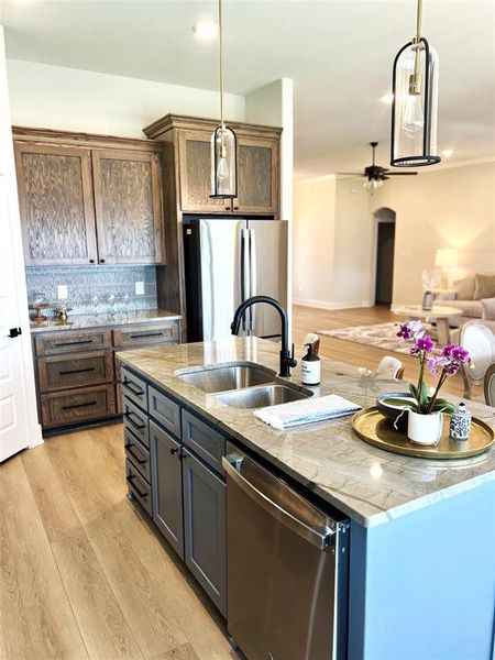 Kitchen with appliances with stainless steel finishes, a sink, a kitchen island with sink, and hanging light fixtures Kitchen with appliances with stainless steel finishes, a sink, a kitchen island with sink, and hanging light fixtures