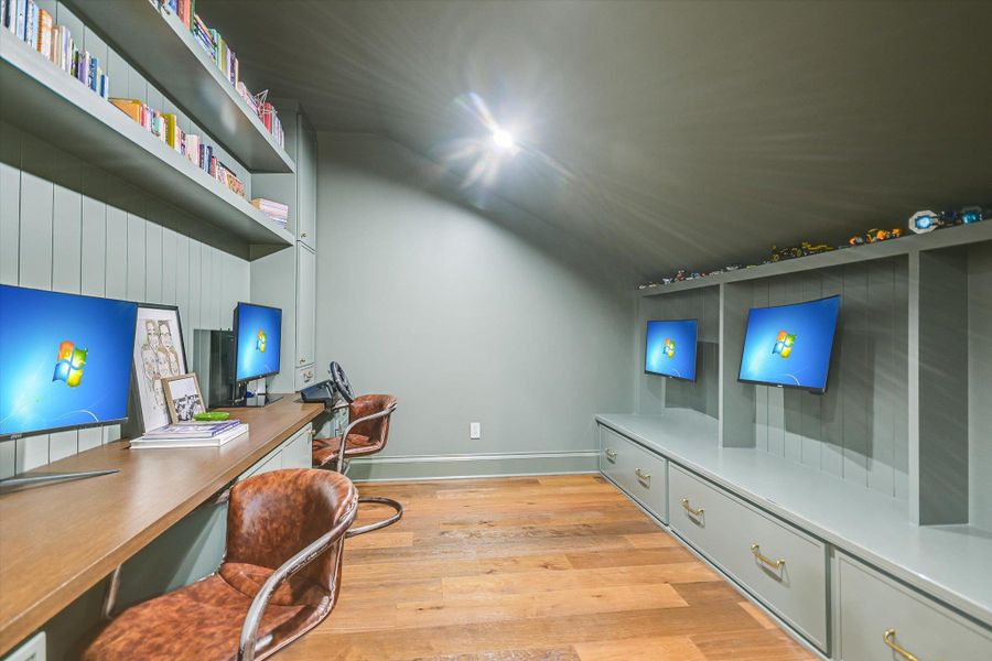 Home office featuring light wood-style floors, vaulted ceiling, and built in study area Home office featuring light wood-style floors, vaulted ceiling, and built in study area
