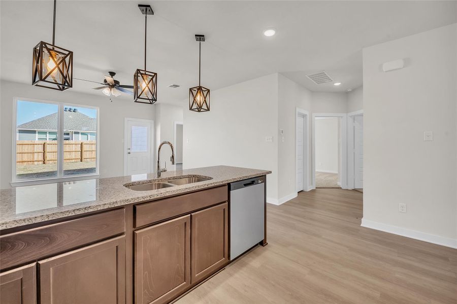 Kitchen featuring visible vents, a sink, light stone counters, light wood-style floors, and dishwasher