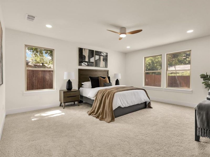 Carpeted bedroom featuring multiple windows and ceiling fan