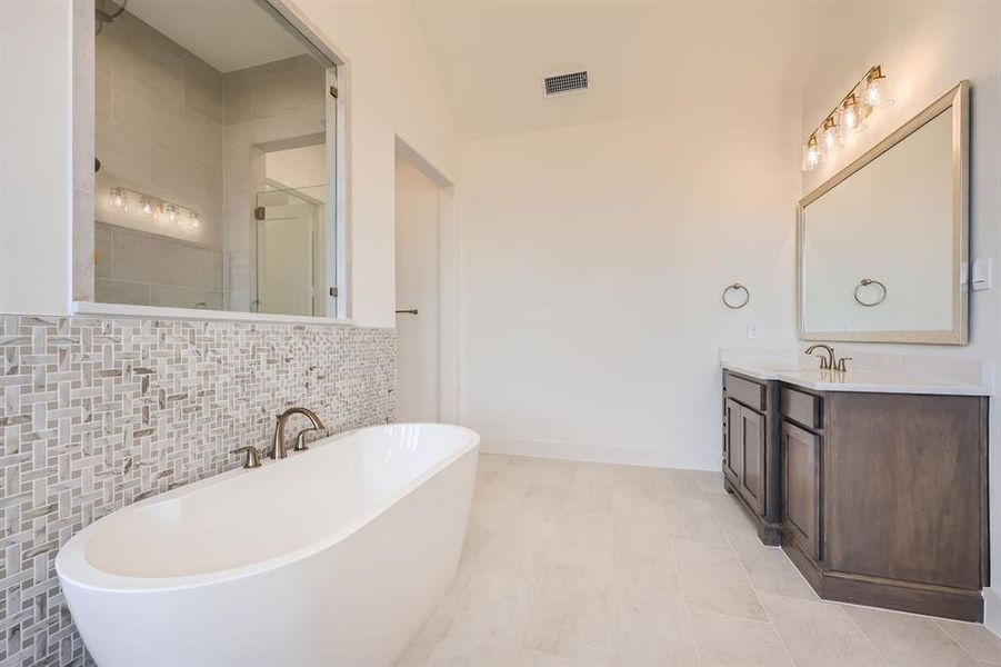 Bathroom with vanity, decorative backsplash, tile patterned flooring, and plus walk in shower