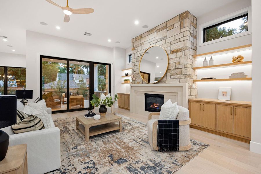 A stunning focal point featuring a floor-to-ceiling stone fireplace that adds texture and warmth to the living space. Custom built-ins with soft integrated lighting provide both display and storage, enhancing the room’s functionality while maintaining a clean, modern aesthetic. The combination of natural materials and tailored details creates a space that feels elevated yet comfortably livable.