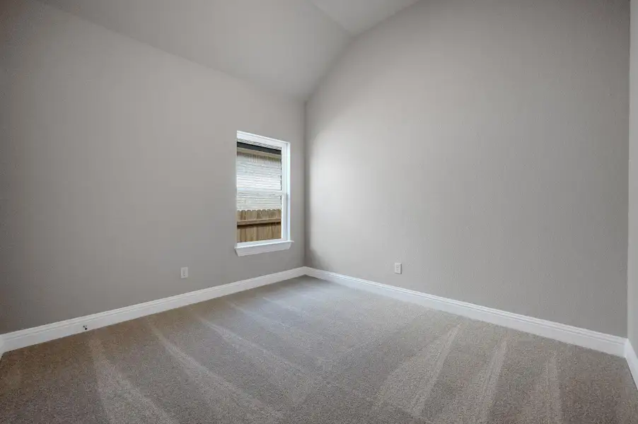 Empty room with vaulted ceiling and carpet floors