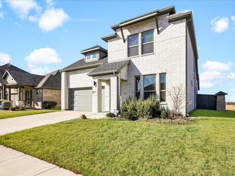 View of front facade featuring a front yard and a garage