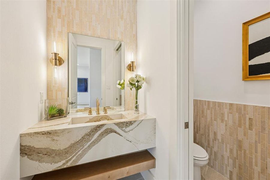 Modern bathroom featuring a floating vanity with an integrated sink, gold-tone fixtures, and complementary wall sconces