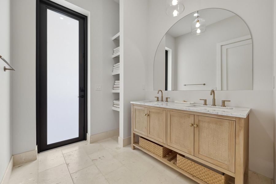 Cabana bath with travertine flooring, double sink, towel storage & custom mirror