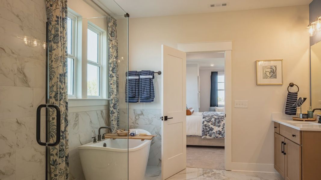 Bright bathroom with frameless glass shower and full tile, separate freestanding tub, and large closet