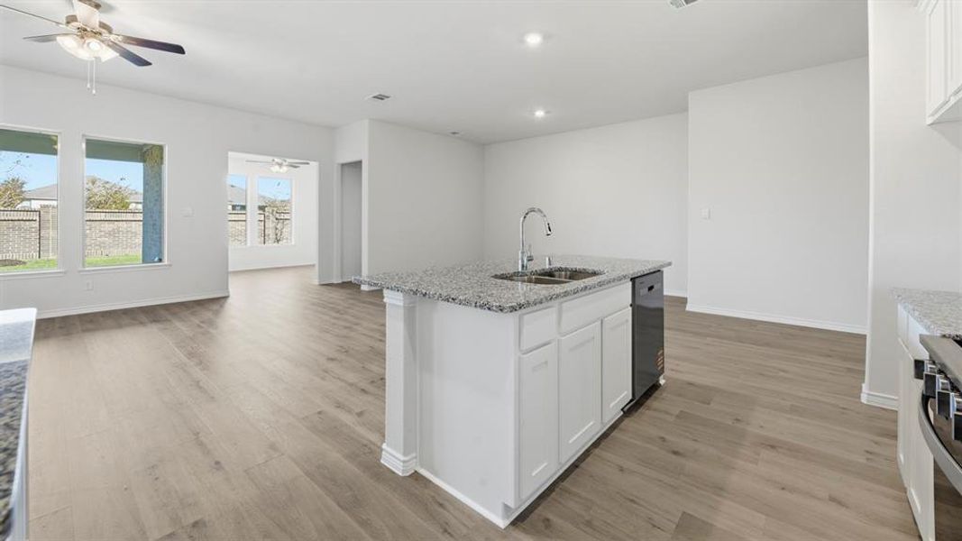 Kitchen featuring light stone countertops, white cabinetry, open floor plan, light wood-style floors, and recessed lighting