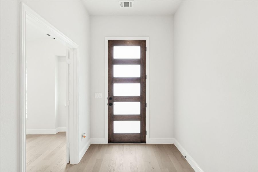 Entryway with dark wood front door featuring five glass panels and light hardwood floors