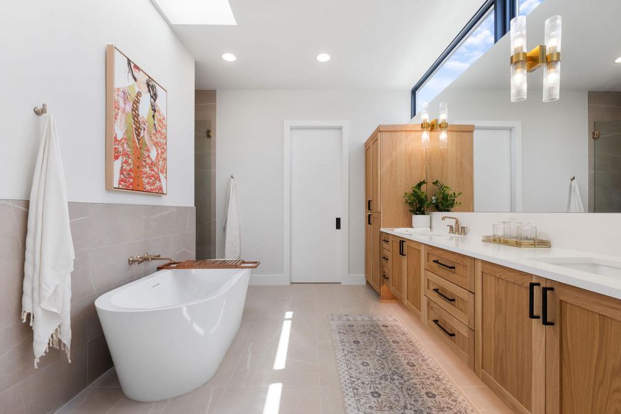 Bathroom with double vanity, tiled shower, a skylight, tile patterned floors, and a soaking tub