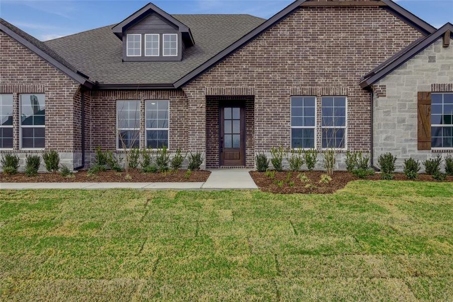 View of front of property featuring a front lawn, brick siding, and roof with shingles