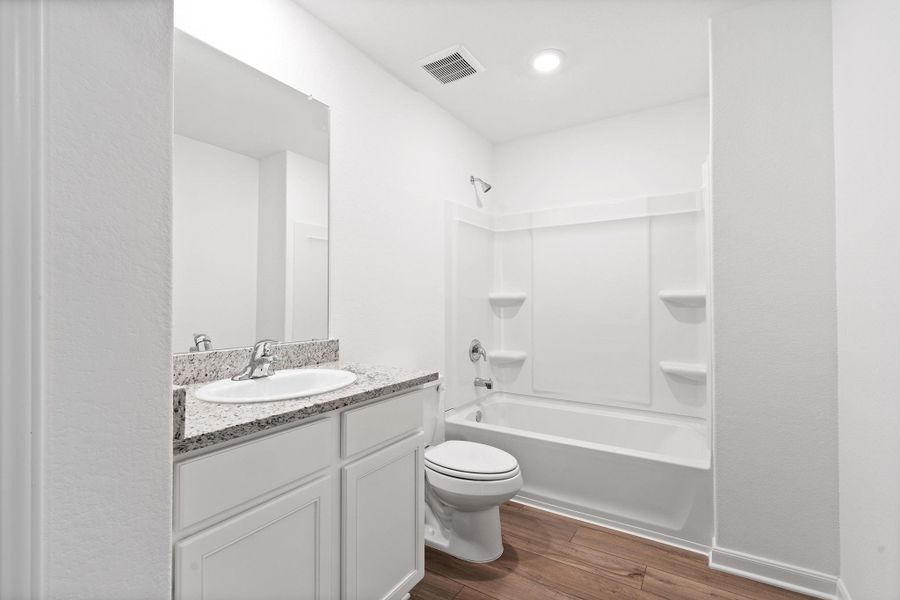 Bathroom with shower / bathtub combination, dark wood finished floors, and vanity