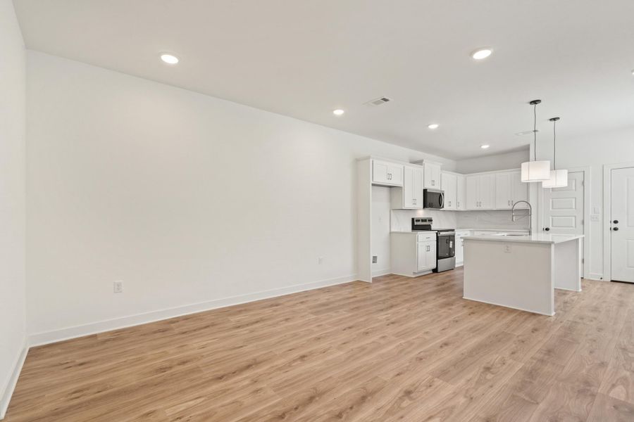 Open-concept living space featuring wood-finish flooring and recessed lighting