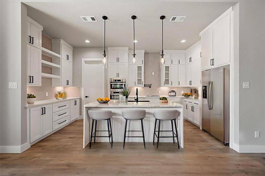 Kitchen featuring light stone countertops, stainless steel appliances, white cabinets, decorative light fixtures, and a kitchen bar Kitchen featuring light stone countertops, stainless steel appliances, white cabinets, decorative light fixtures, and a kitchen bar