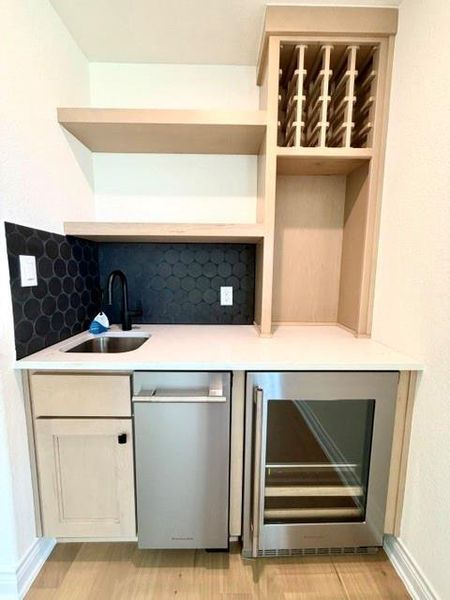 A wet bar features open shelving, built-in wine storage, and modern appliances for entertaining. A wet bar features open shelving, built-in wine storage, and modern appliances for entertaining.