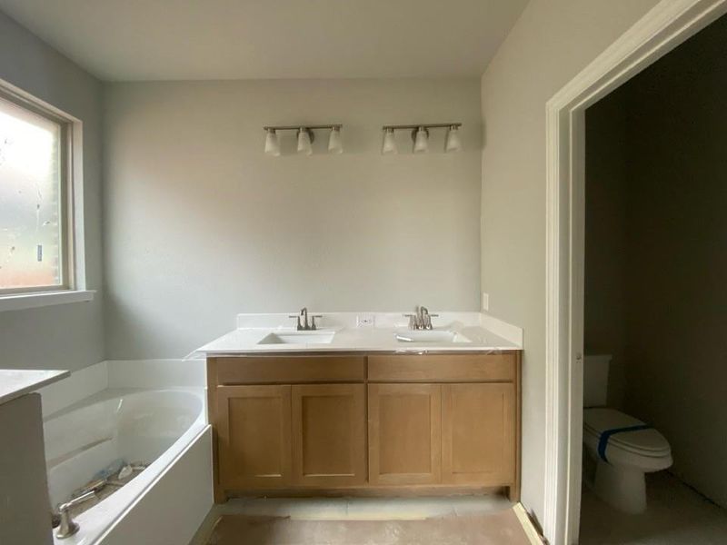 Bathroom featuring a double vanity with light wood-finish cabinetry and white countertops