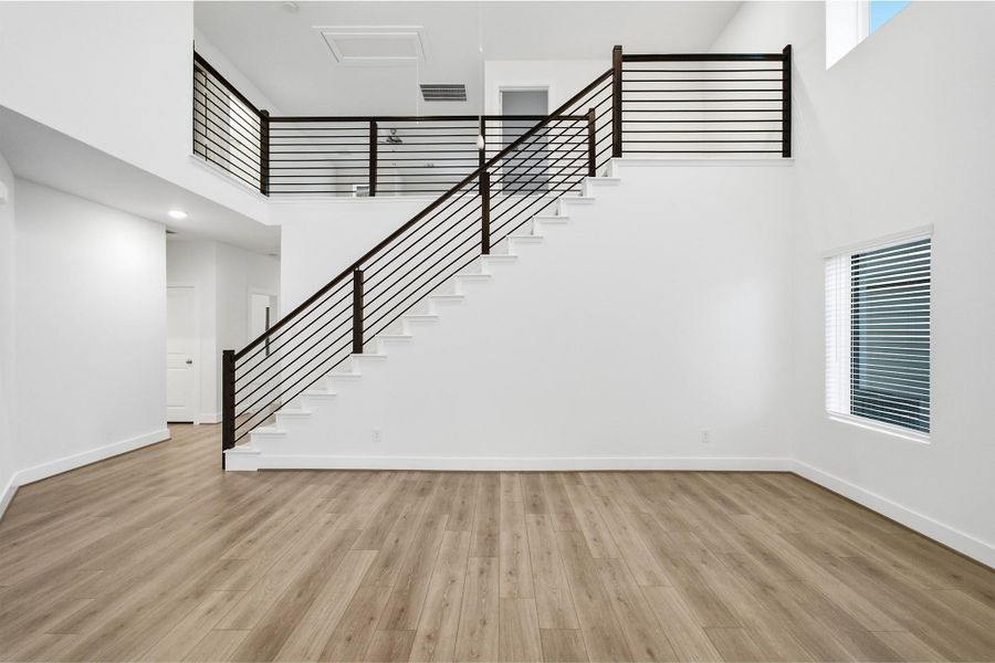 Unfurnished living room with a high ceiling, light wood-style flooring, healthy amount of natural light, and recessed lighting