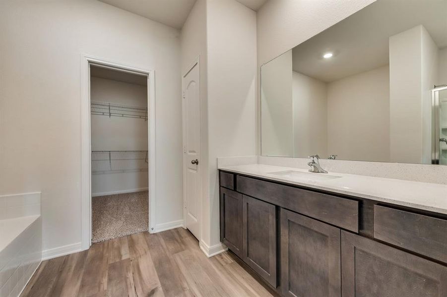 Bathroom with a bathtub, oversized vanity, and hardwood / wood-style flooring