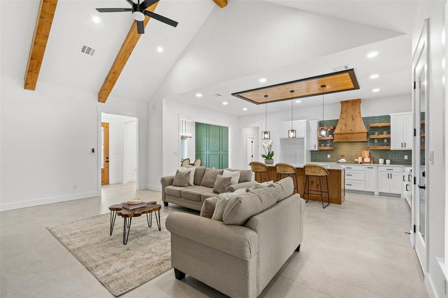 Living area with baseboards, visible vents, high vaulted ceiling, beam ceiling, and recessed lighting