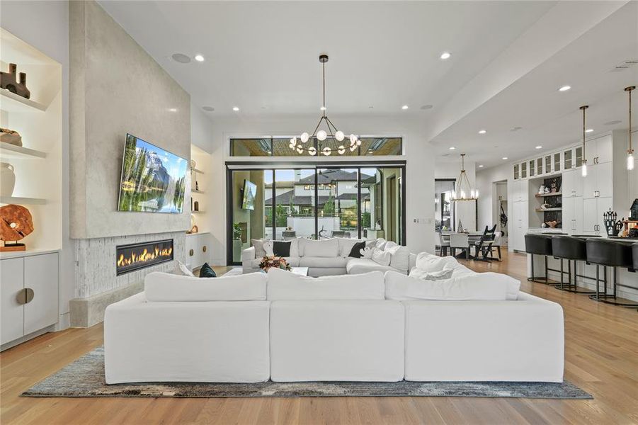 Living room with light wood-type flooring, a chandelier, a fireplace, and recessed lighting Living room with light wood-type flooring, a chandelier, a fireplace, and recessed lighting