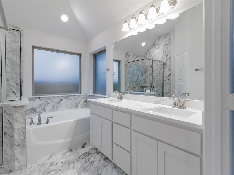 Bathroom featuring vanity, independent shower and bath, and vaulted ceiling