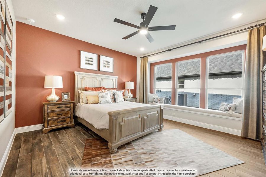Bedroom with rust-colored accent wall, wood-look floors, ceiling fan, and large windows with a built-in window seat Bedroom with rust-colored accent wall, wood-look floors, ceiling fan, and large windows with a built-in window seat