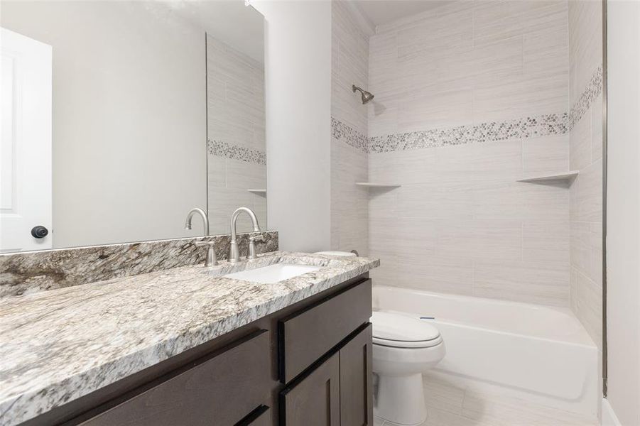 Full bathroom featuring toilet, tiled shower / bath combo, vanity, and tile patterned floors