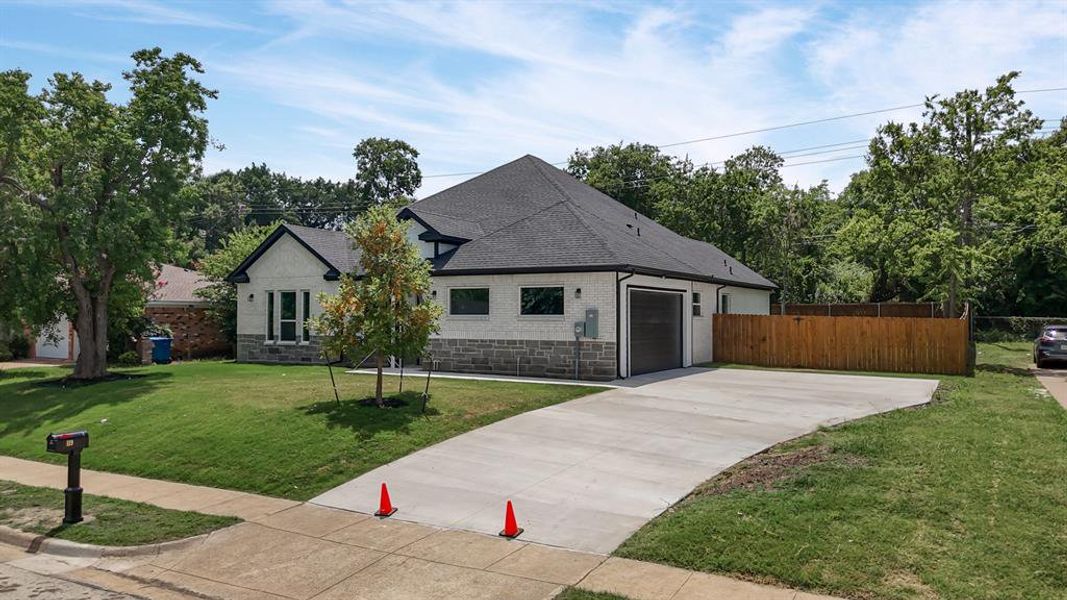 French country inspired facade with stone siding, roof with shingles, concrete driveway, and a double garage French country inspired facade with stone siding, roof with shingles, concrete driveway, and a double garage