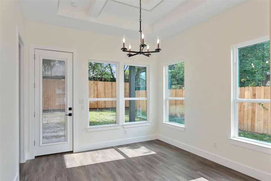 Unfurnished dining area featuring dark wood-style flooring, a chandelier, and a raised ceiling Unfurnished dining area featuring dark wood-style flooring, a chandelier, and a raised ceiling