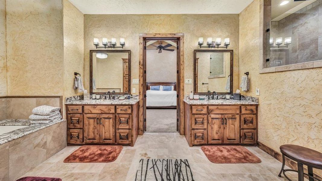 Dual vanities with granite counters, framed mirrors, and a view into the primary suite enhance both style and functionality.