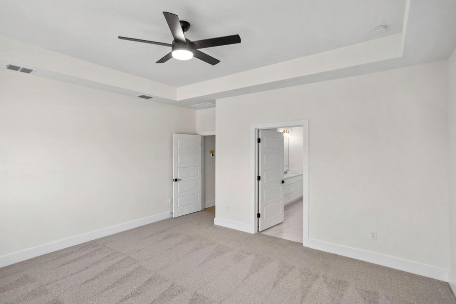 Spacious interior room featuring a tray ceiling with a contemporary ceiling fan and light fixture Spacious interior room featuring a tray ceiling with a contemporary ceiling fan and light fixture