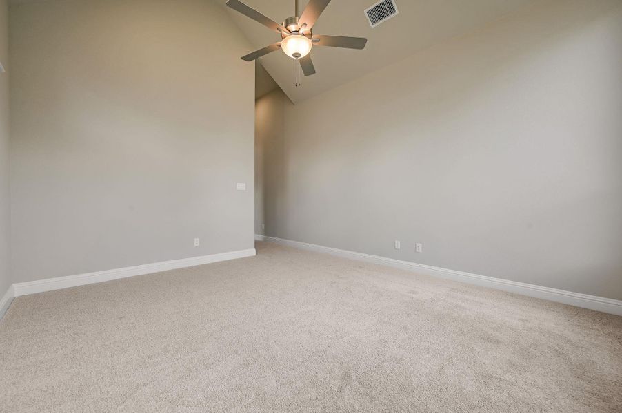 Empty room featuring light carpet, high vaulted ceiling, and ceiling fan
