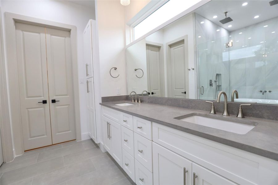 This stylish primary en suite features ample storage with dual drawer sets, a leather-finished 3 CM quartz countertop, and a striking designer faucet. A custom wall-to-wall mirror is topped by a sleek horizontal privacy window, brightening the space with soft, natural light. This stylish primary en suite features ample storage with dual drawer sets, a leather-finished 3 CM quartz countertop, and a striking designer faucet. A custom wall-to-wall mirror is topped by a sleek horizontal privacy window, brightening the space with soft, natural light.