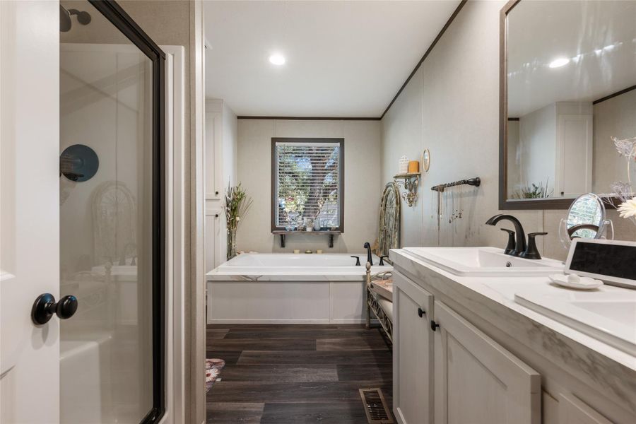 Bathroom with a stall shower, double vanity, a garden tub, dark wood-style floors, and recessed lighting