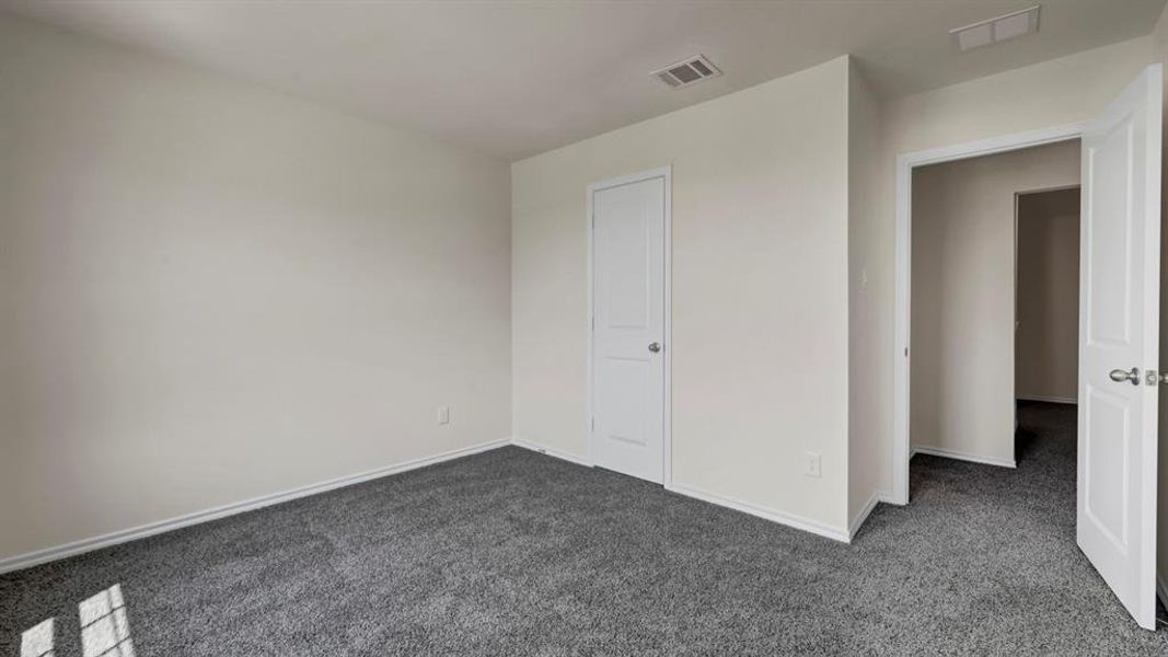 Spacious room featuring neutral paint, gray carpeting, a paneled door, and white baseboards