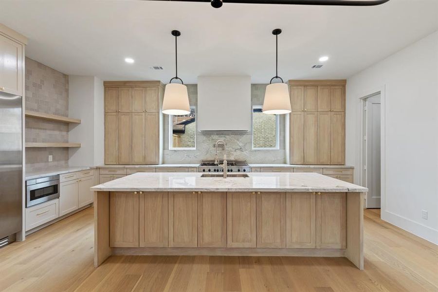 The kitchen is a true chef’s dream, featuring stunning quartzite countertops, a custom plaster vent hood, white oak custom cabinets, and Bertazzoni 48-inch range and refrigerator columns, offering both beauty and practicality.