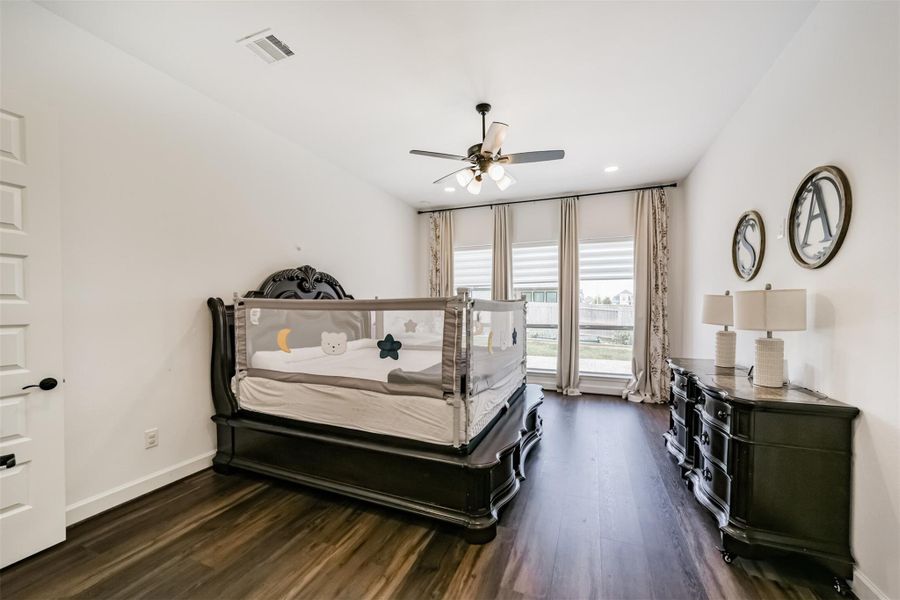 The primary bedroom is conveniently located on the ground floor and features a cozy sitting area, large windows adorned with elegant treatments, and a ceiling fan with an integrated light fixture. The primary bedroom is conveniently located on the ground floor and features a cozy sitting area, large windows adorned with elegant treatments, and a ceiling fan with an integrated light fixture.